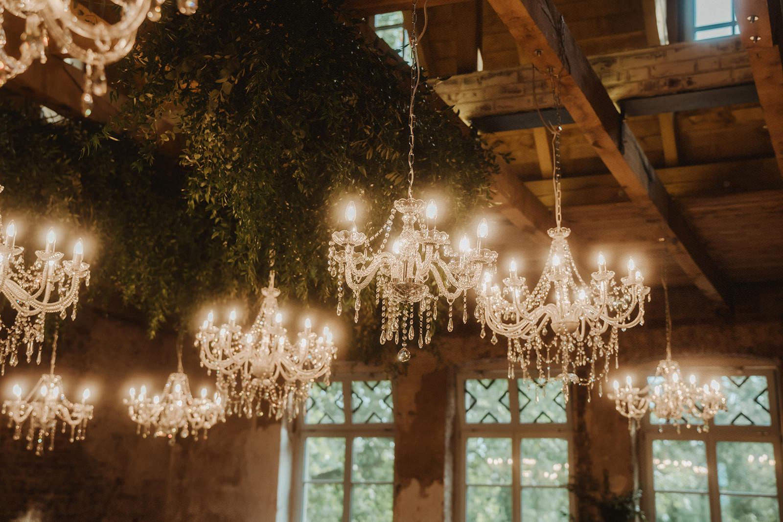 Kronleuchter und Greenery hängen unter der Decke des Festsaals von Rittergut Orr | Hochzeitsplanung: Sagt Ja